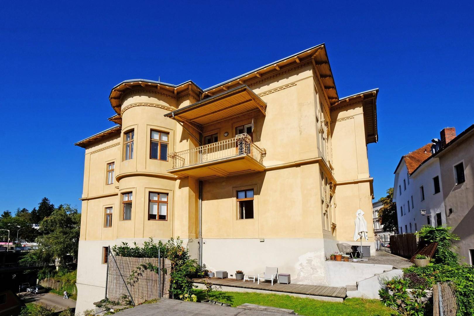 Seitenansicht der Villa mit kleiner Terrasse und Sitzgelegenheiten im Freien.