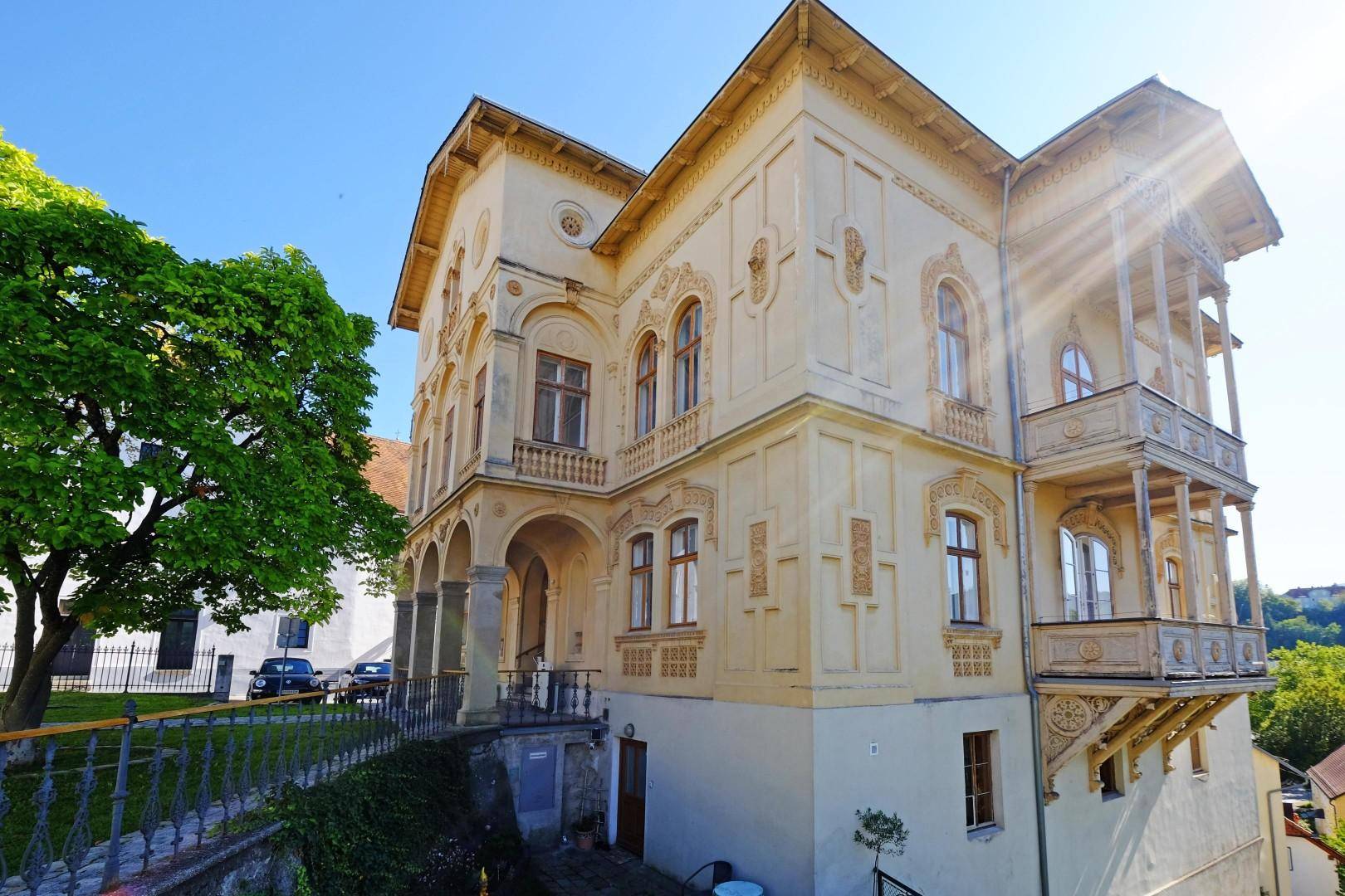 Seitenansicht der historischen Villa mit eleganten Balkonen und Blick auf die Umgebung.