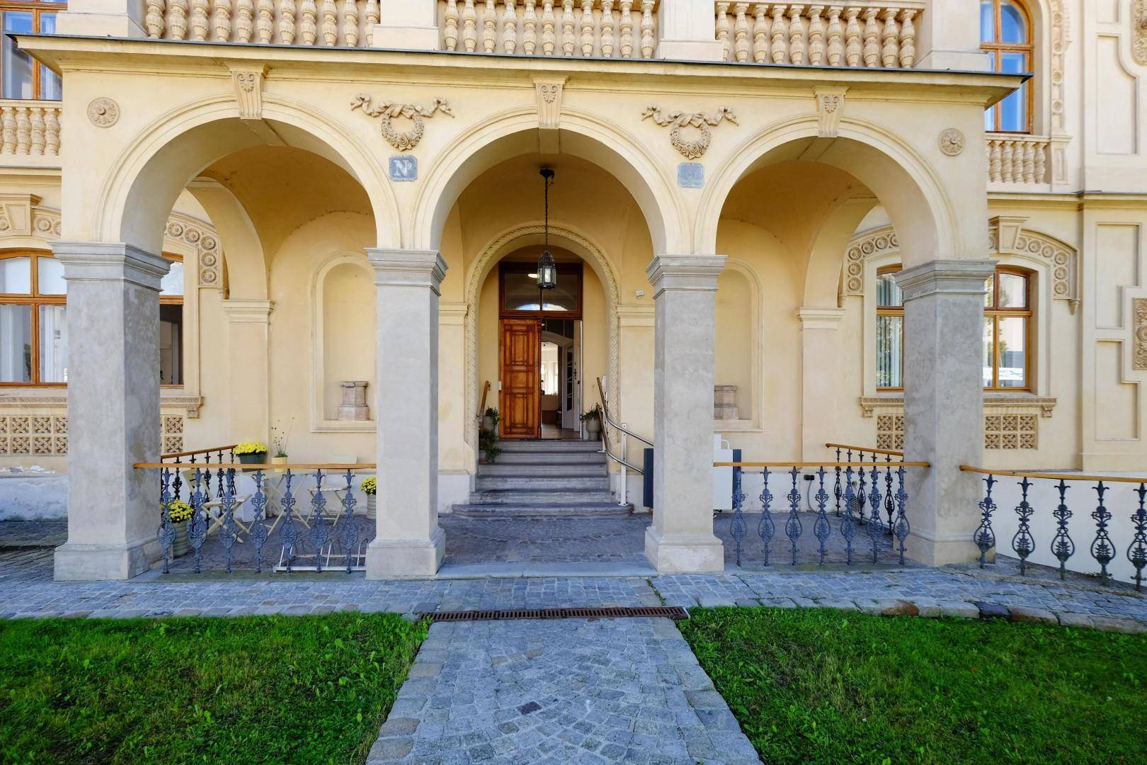 Repräsentativer Eingangsbereich der Villa mit Säulen, Bögen und schmiedeeisernem Geländer.
