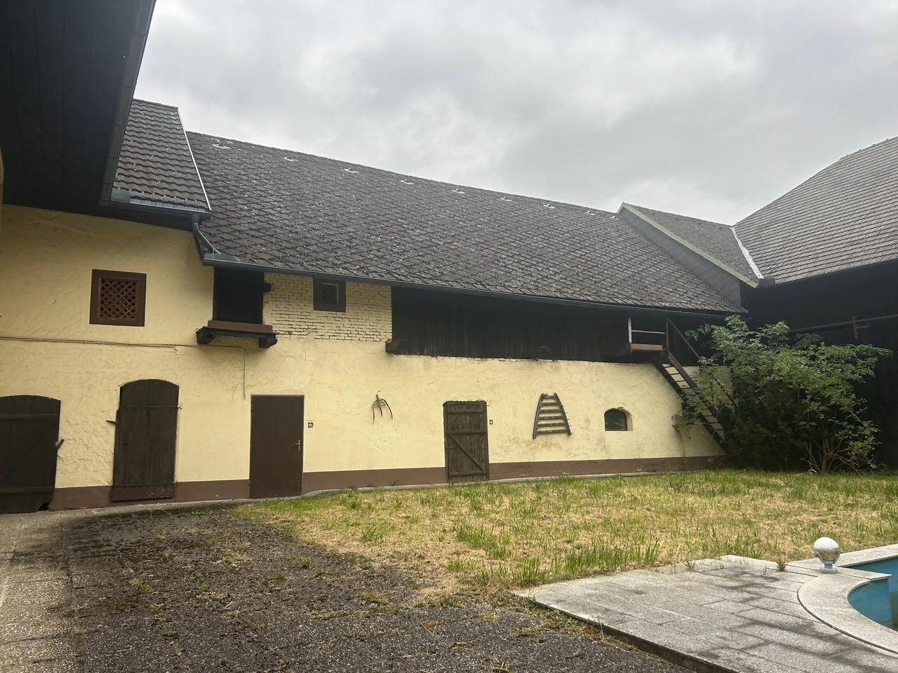 Innenhof eines Gebäudekomplexes mit Rasenfläche, Holztreppe und einem kleinen Wasserbecken.