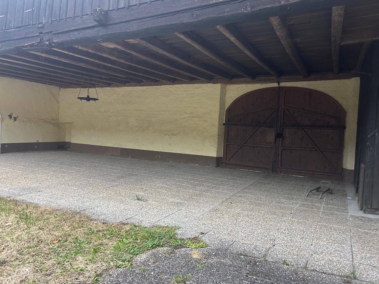 Überdachter Außenbereich mit Holzbalken und großen Holztoren, ideal als Carport oder Lagerfläche.
