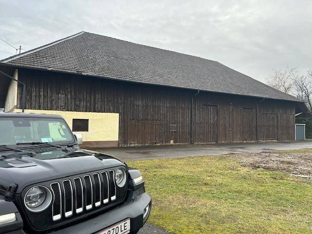Große Holzscheune mit doppelten Toren und dunkler Holzfassade neben dem Hauptgebäude.