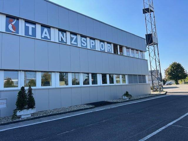 Seitenansicht eines modernen Geschäftsgebäudes mit großen Fenstern und einer Metallfassade.