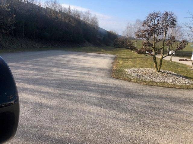 Großer asphaltierter Parkplatz mit Bäumen und Grünflächen, ideal für Mitarbeiter und Besucher.