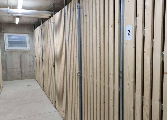 Kellerabteile mit Holzwänden und nummerierten Türen, ideal für zusätzlichen Stauraum.