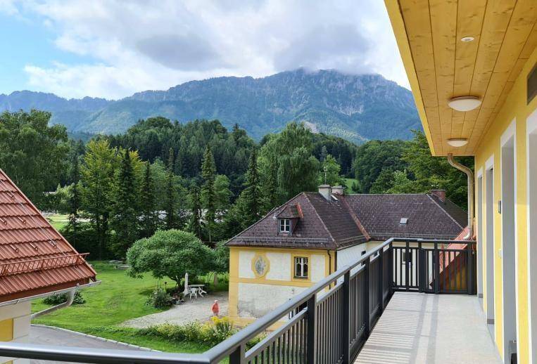 Langer Balkon mit Bergblick und grüner Umgebung, ideal zum Entspannen im Freien.