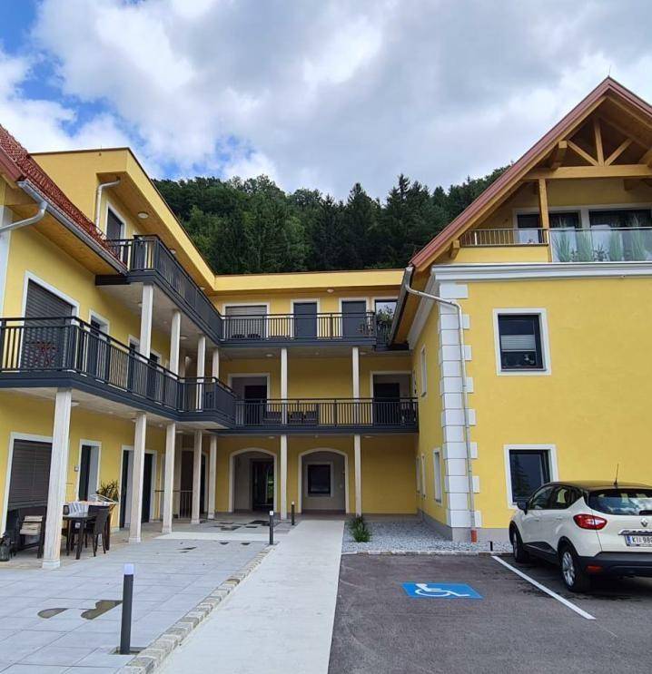 Gelbes Mehrfamilienhaus mit mehreren Balkonen und einem barrierefreien Zugangsbereich.