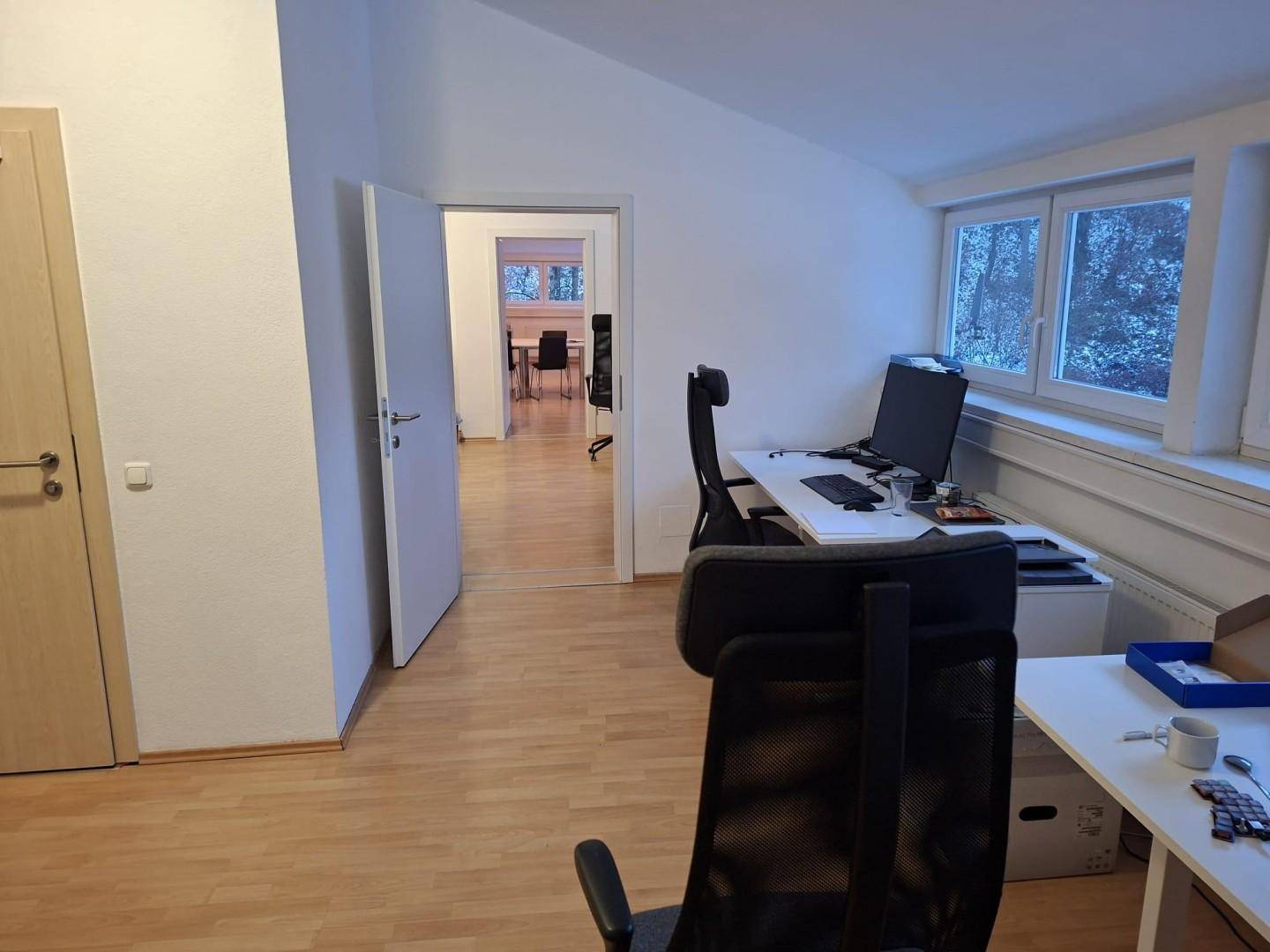 Geräumiger Bürobereich mit mehreren Arbeitsplätzen und Zugang zu weiteren Räumen, hell und funktional.