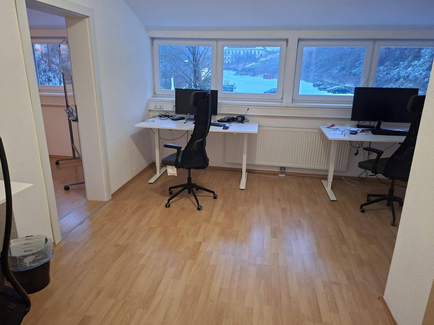 Heller Büroraum mit zwei Arbeitsplätzen, ergonomischen Stühlen und Blick auf die verschneite Umgebung.