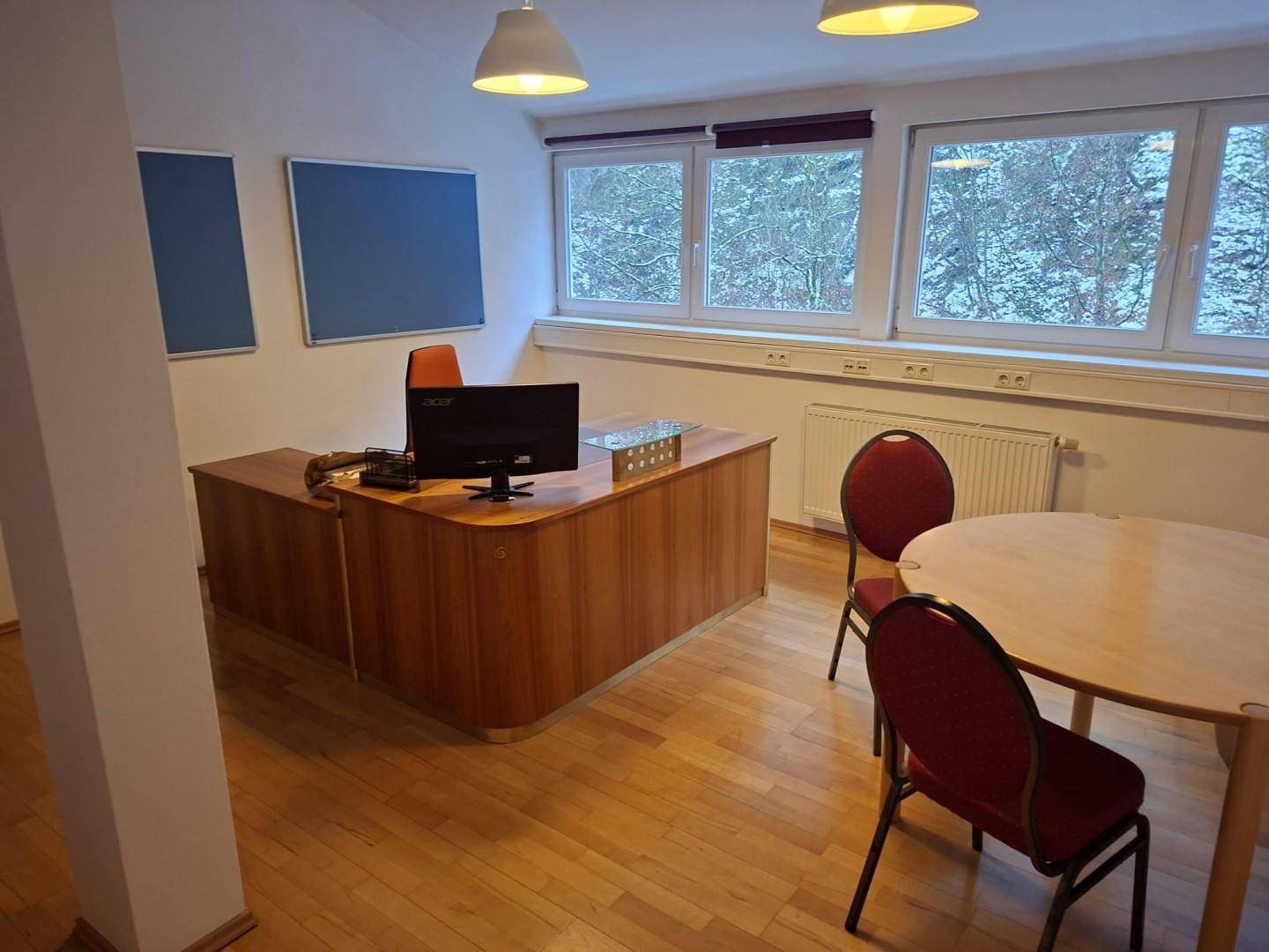 Großes Büro mit Holzschreibtisch, runden Tischen und blauen Akzenten an den Wänden.