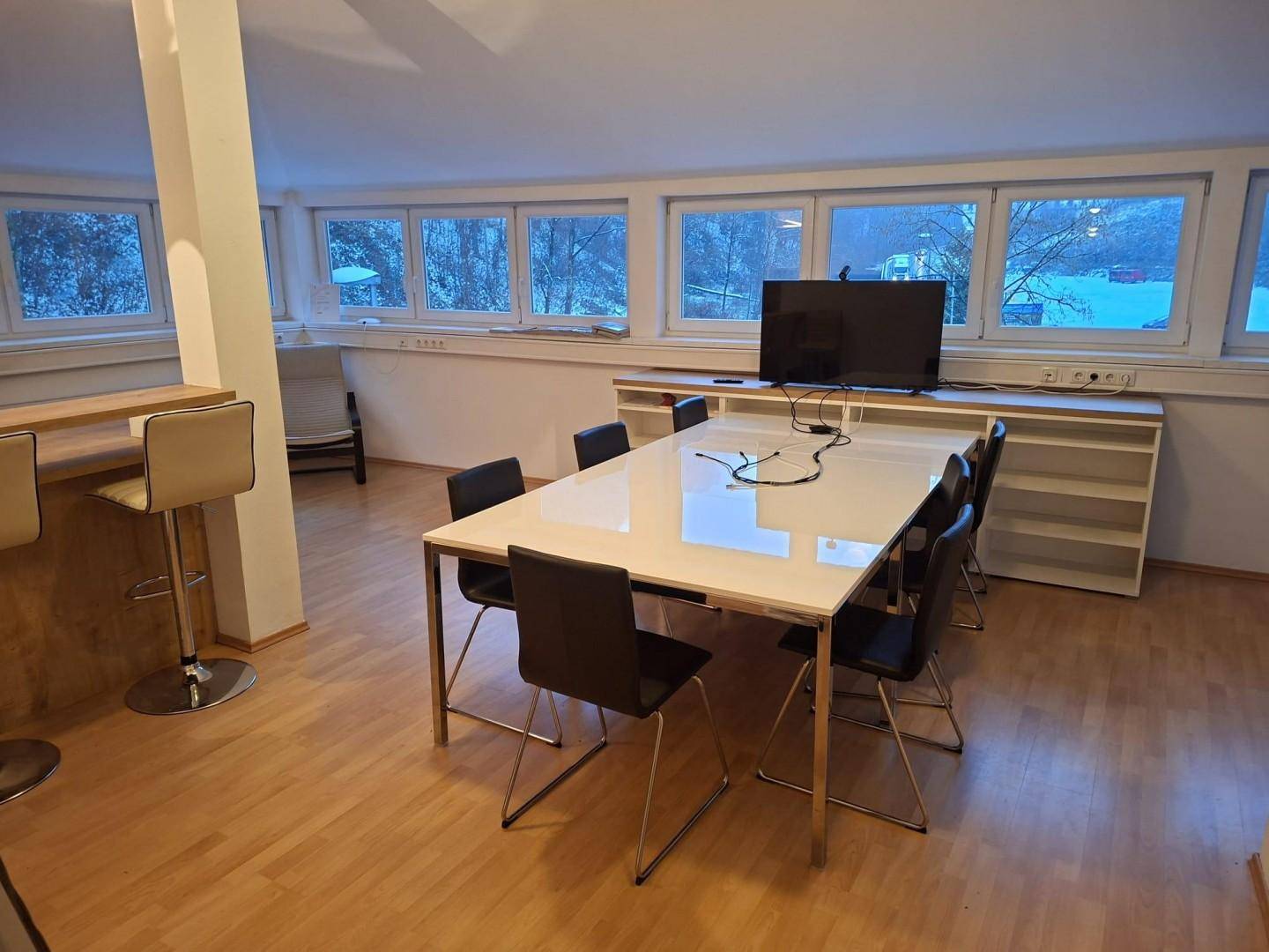 Heller Essbereich mit großem Tisch und Blick auf die verschneite Umgebung, angrenzend an eine offene Küche.