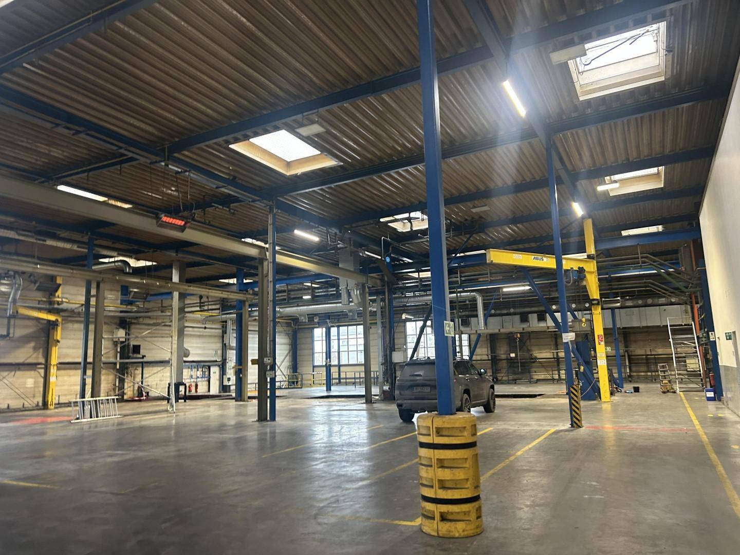 Geräumige Industriehalle mit hohen Decken, Oberlichtern und sichtbaren Stahlträgern, bereit für den Betrieb und gut beleuchtet.