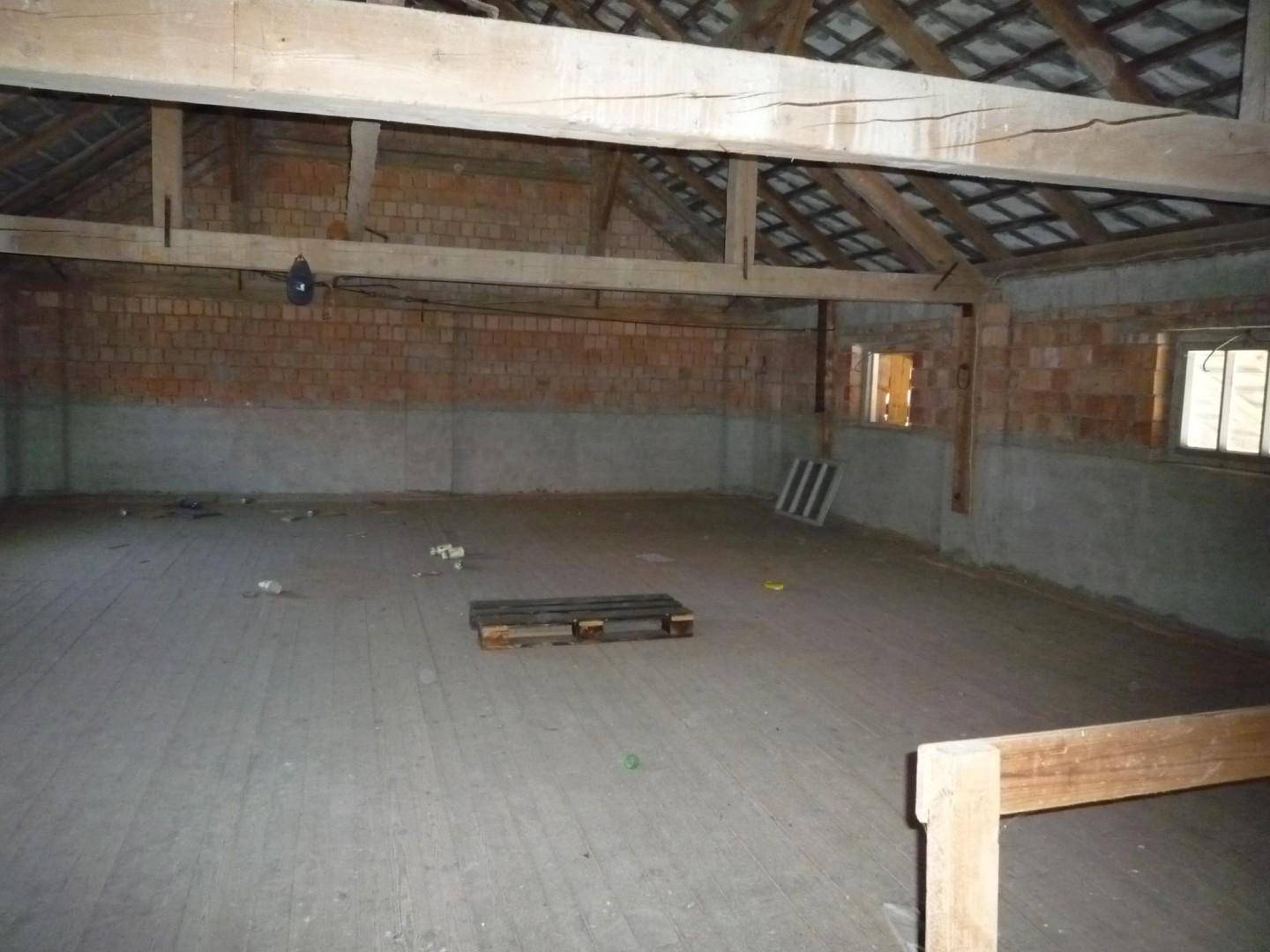 Geräumiger Dachboden mit sichtbaren Holzbalken und Ziegelwänden, ungenutzt.