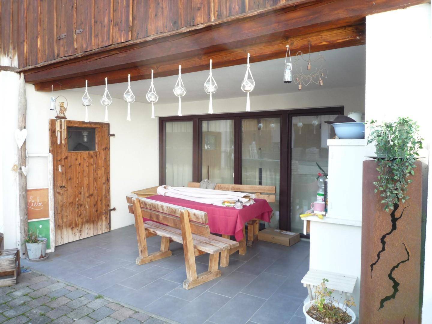 Überdachte Terrasse mit Holzbänken und Esstisch, ideal für Mahlzeiten im Freien.