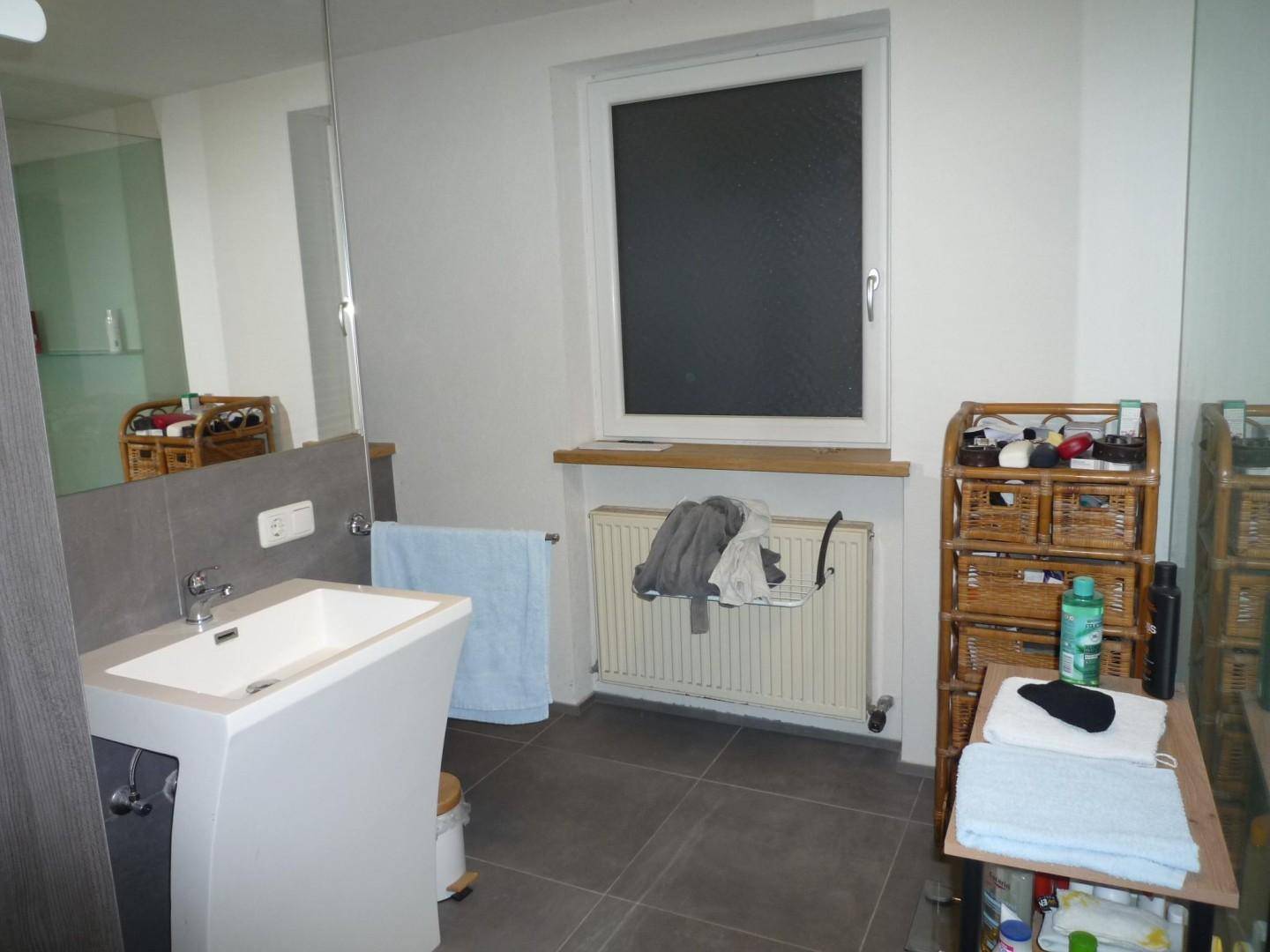 Modernes Badezimmer mit großformatigen Fliesen, Einzelwaschbecken und Fenster.