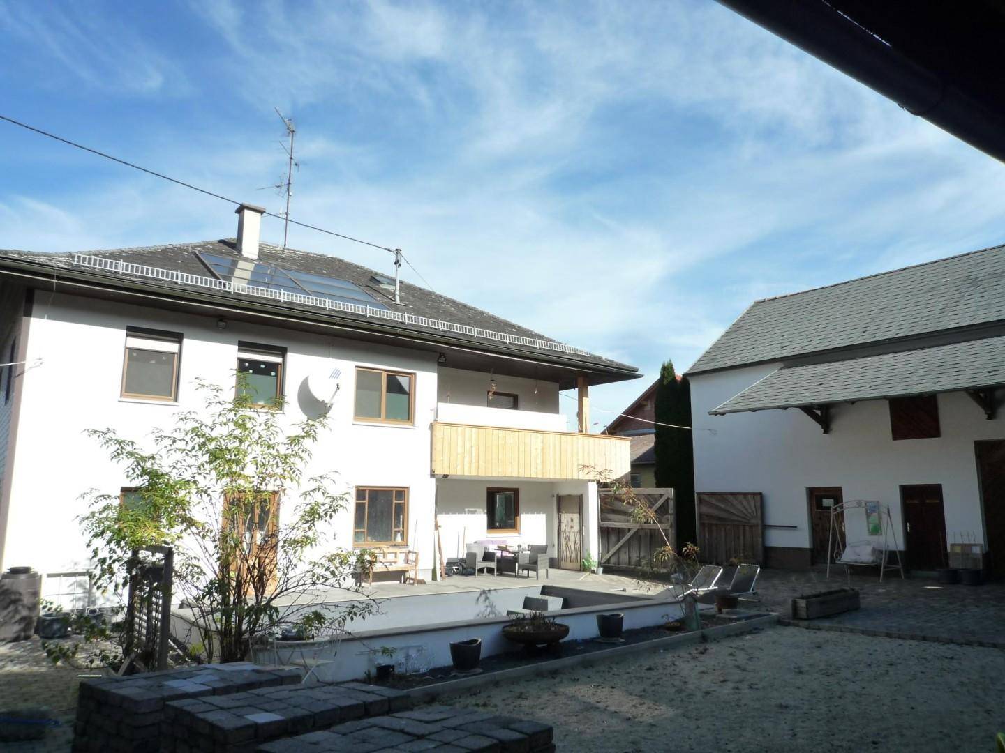 Rückseite des Hauses mit Poolbereich, Terrasse und einem weiteren Gebäude im Hintergrund.