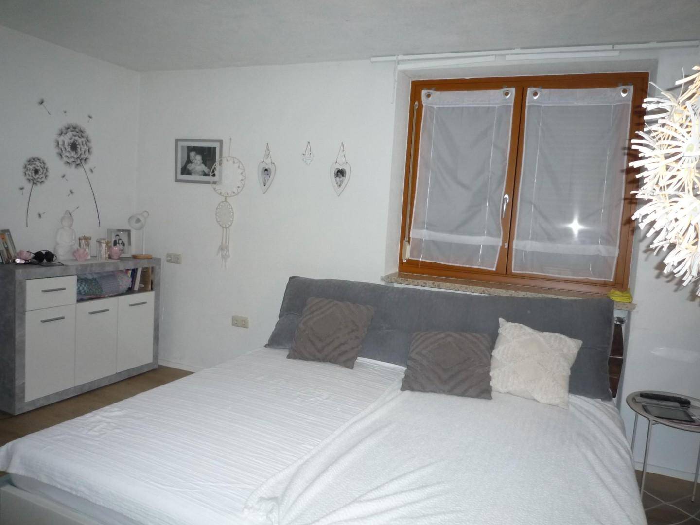 Helles Schlafzimmer mit Doppelbett, minimalistischer Dekoration und großem Fenster.