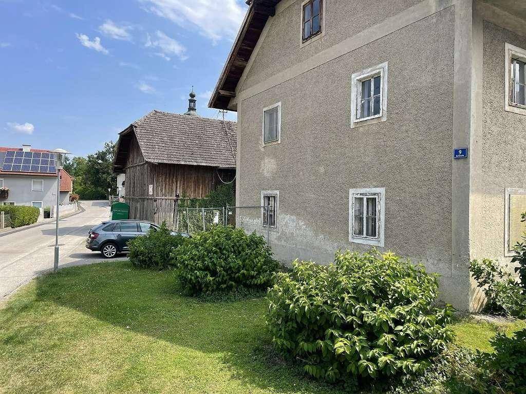 Seitenansicht des alten Gebäudes mit gepflegtem Vorgarten und Blick auf die Dorfstraße.