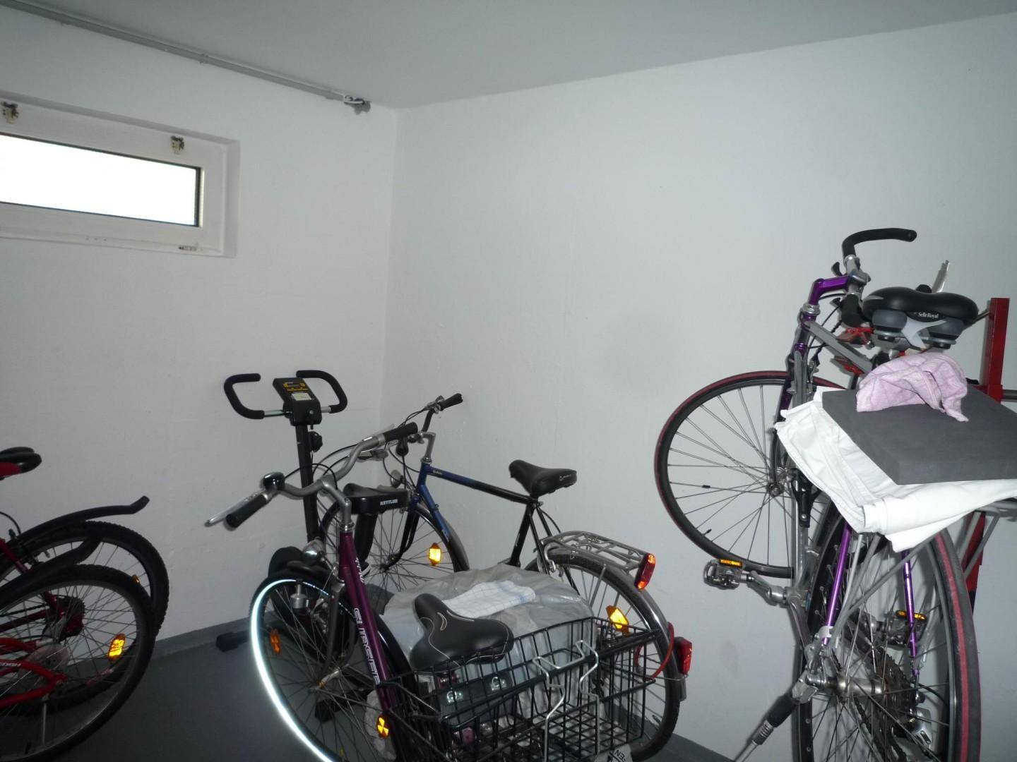 Fahrradraum im Keller mit mehreren Fahrrädern und einem Heimtrainer.