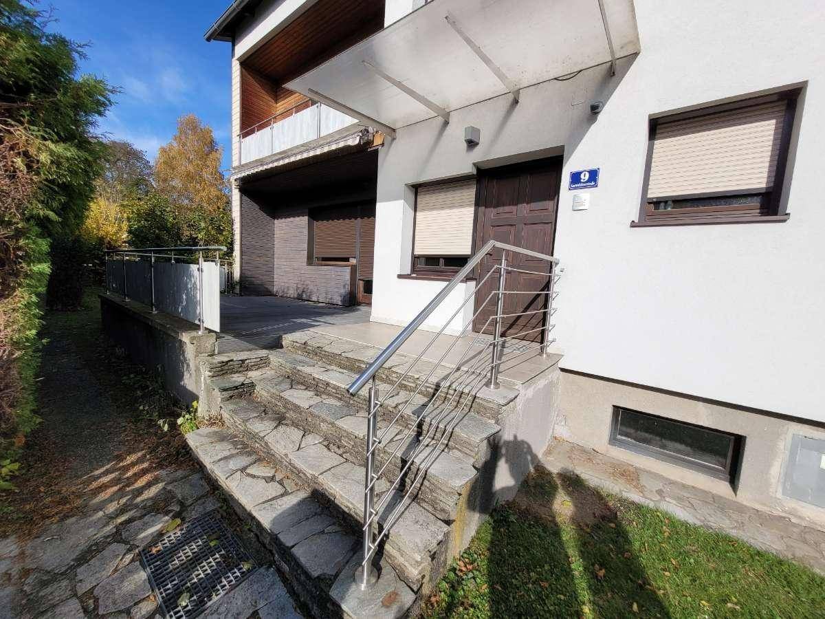 Eingangsbereich des Hauses mit Steintreppe, Edelstahlgeländer und Vordach.