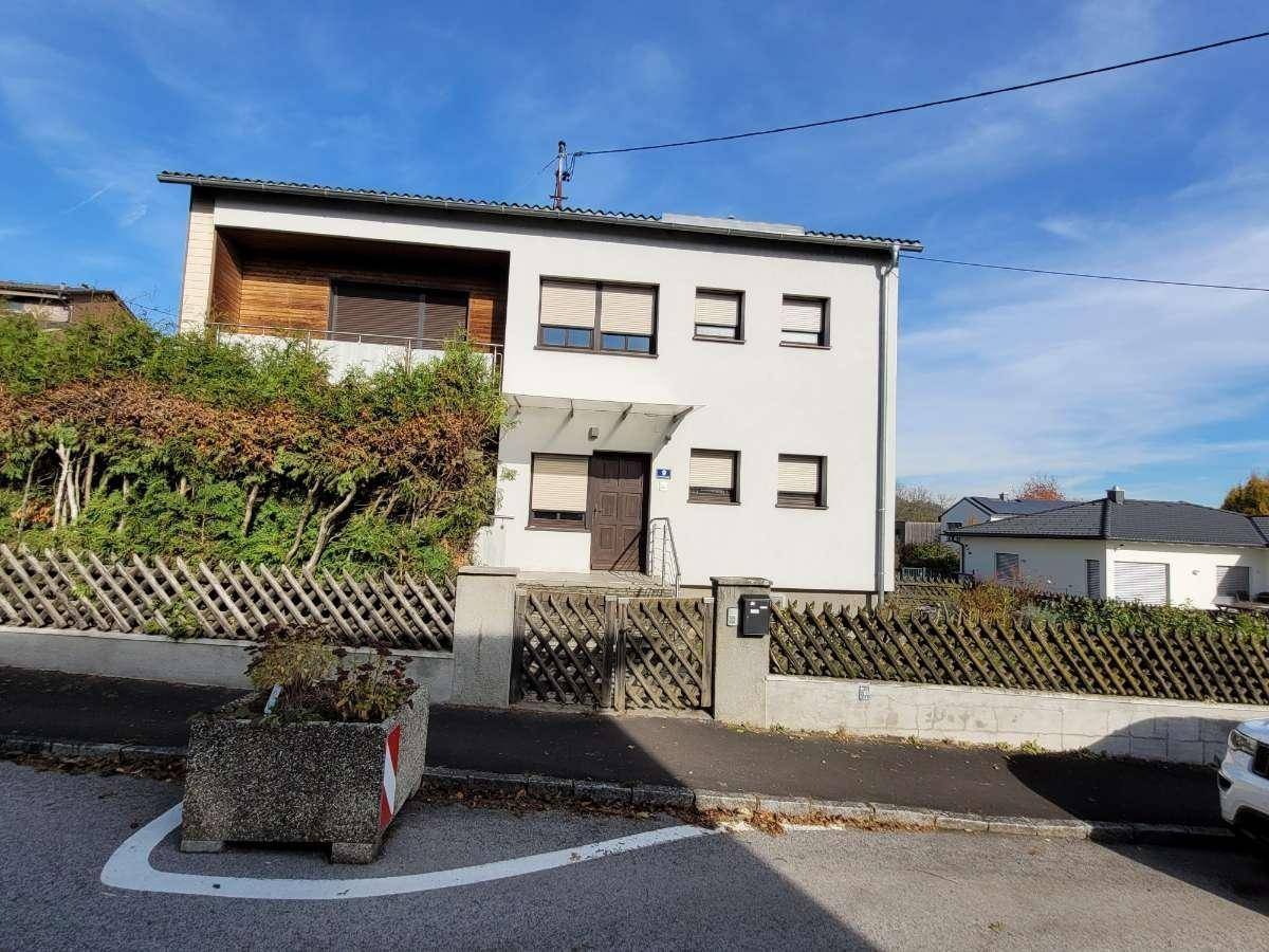 Vorderansicht des Hauses mit Eingangsbereich, Balkon und gepflegter Hecke.