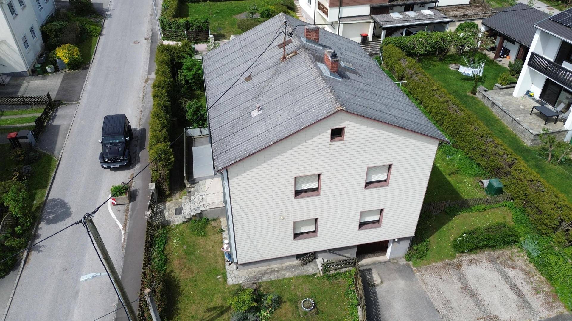 Draufsicht auf das Einfamilienhaus mit Satteldach, Garten und angrenzender Straße.
