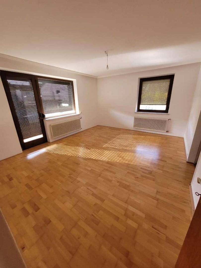 Helles Wohnzimmer mit Parkettboden, großen Fenstern und Zugang zum Balkon.
