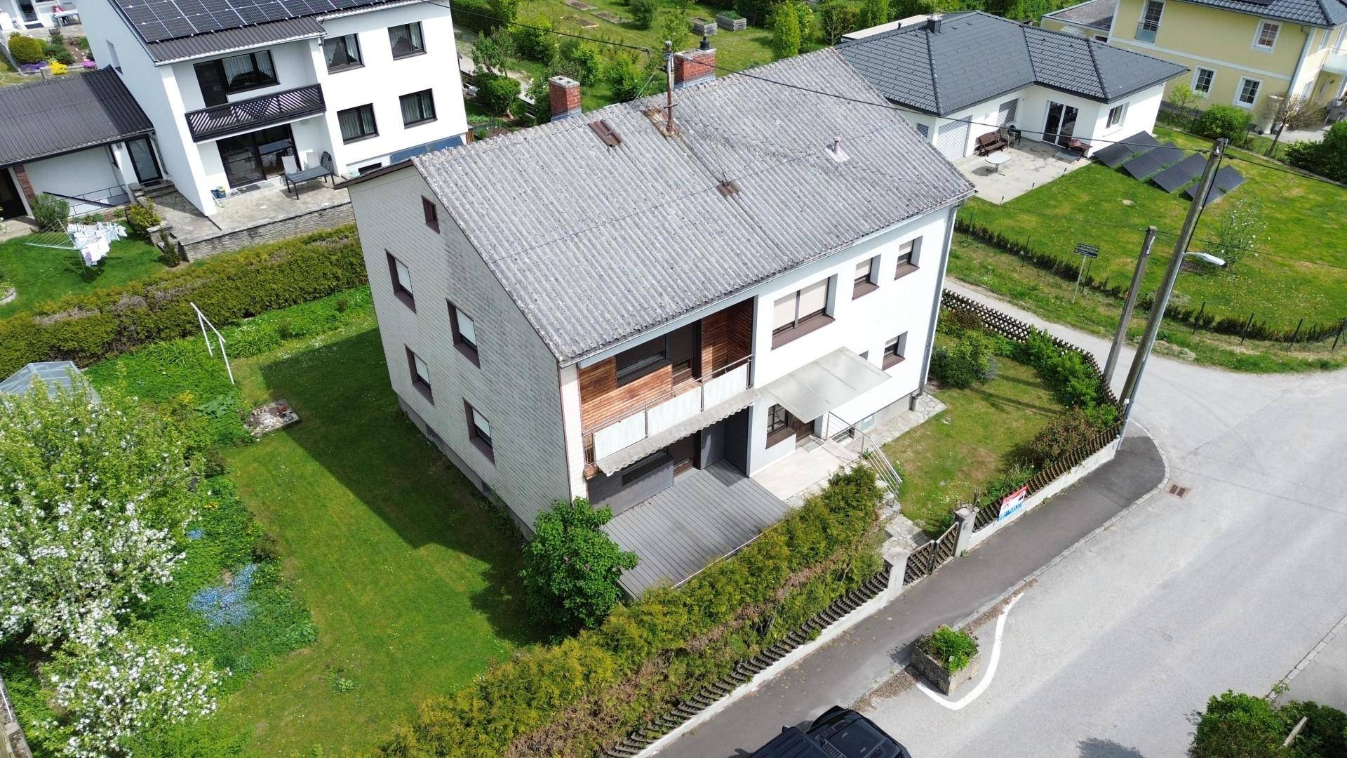Luftaufnahme des Wohnhauses mit Balkon, Terrasse und gepflegtem Gartenbereich.