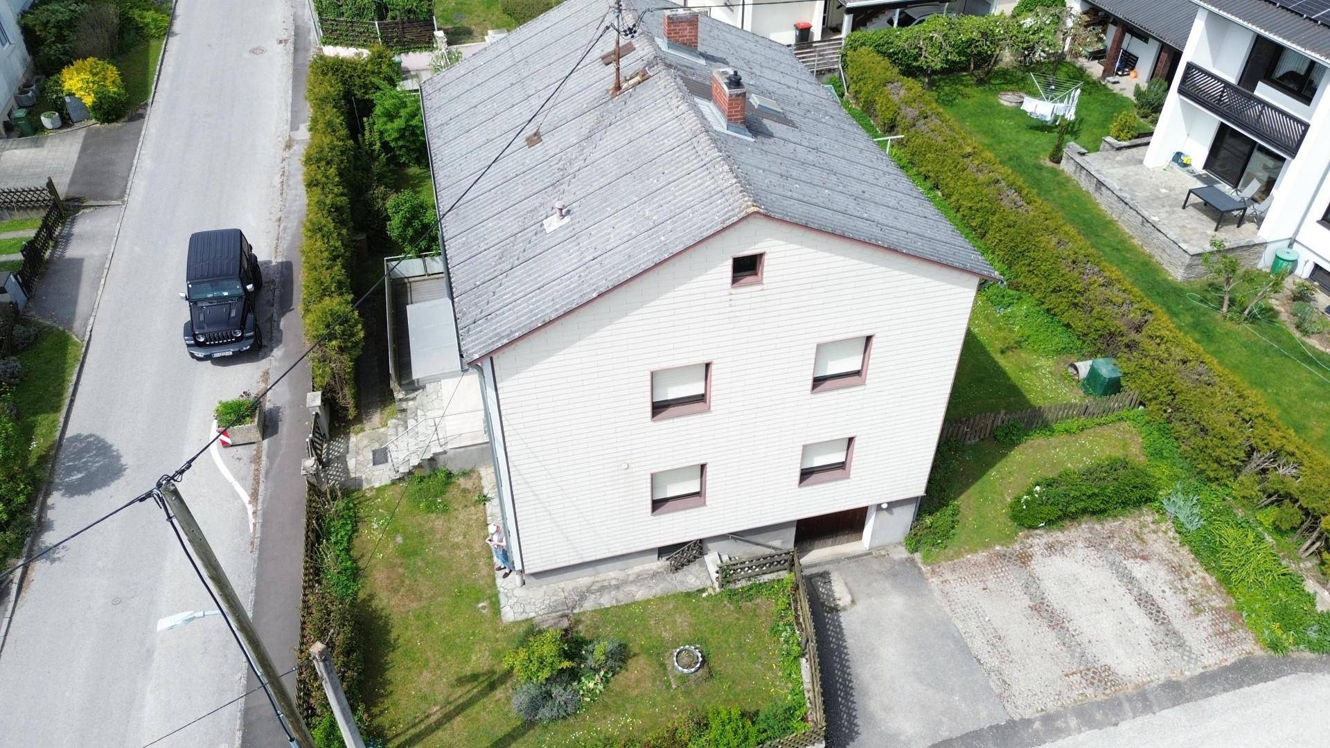Vogelperspektive des Hauses mit Garten, Zufahrt und angrenzender Straße.