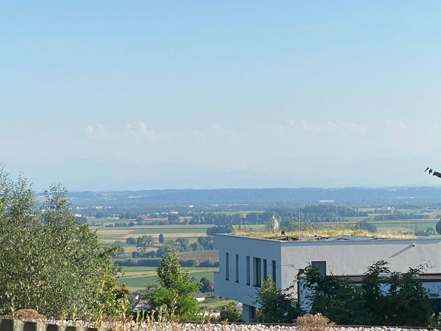 Weitblick über die Landschaft mit Feldern und einer fernen Bergkette am Horizont.