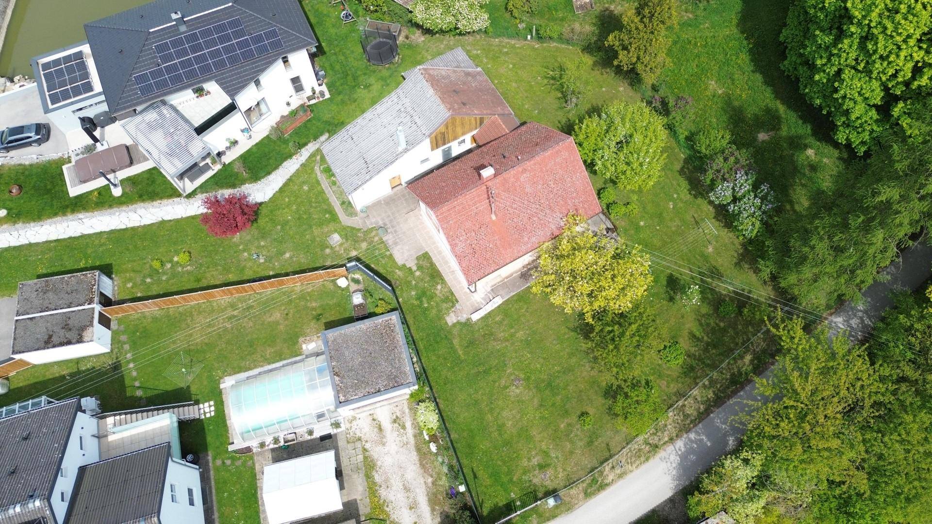 Luftaufnahme des Hauses mit großem Grundstück, angrenzenden Nachbarhäusern und viel Grün.