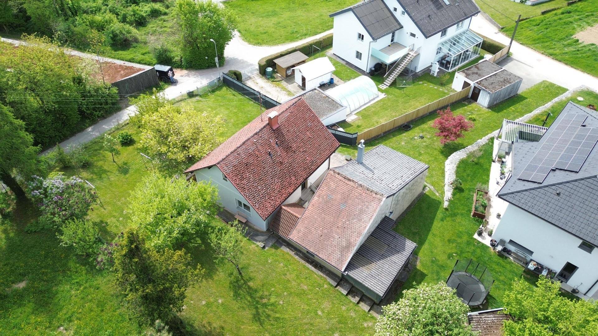 Draufsicht auf das Wohnhaus mit Nebengebäude, umgeben von weitläufigen Grünflächen.