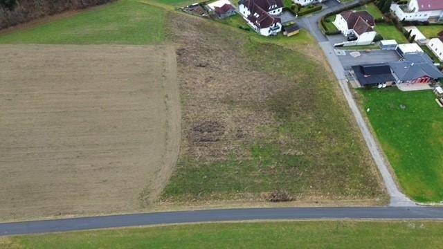 Überblick über ein Wohngebiet und ein großes, unbebautes Grundstück, umgeben von landwirtschaftlichen Flächen.
