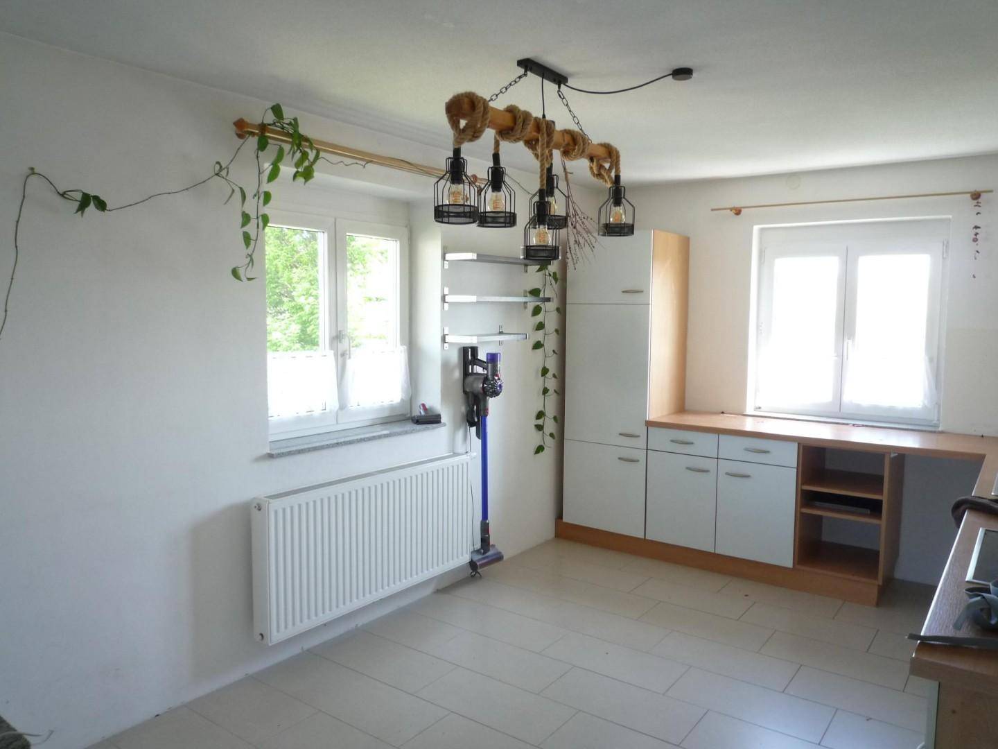 Heller Raum mit Fliesenboden, Einbauschränken und zwei Fenstern, möglicherweise eine Küche.