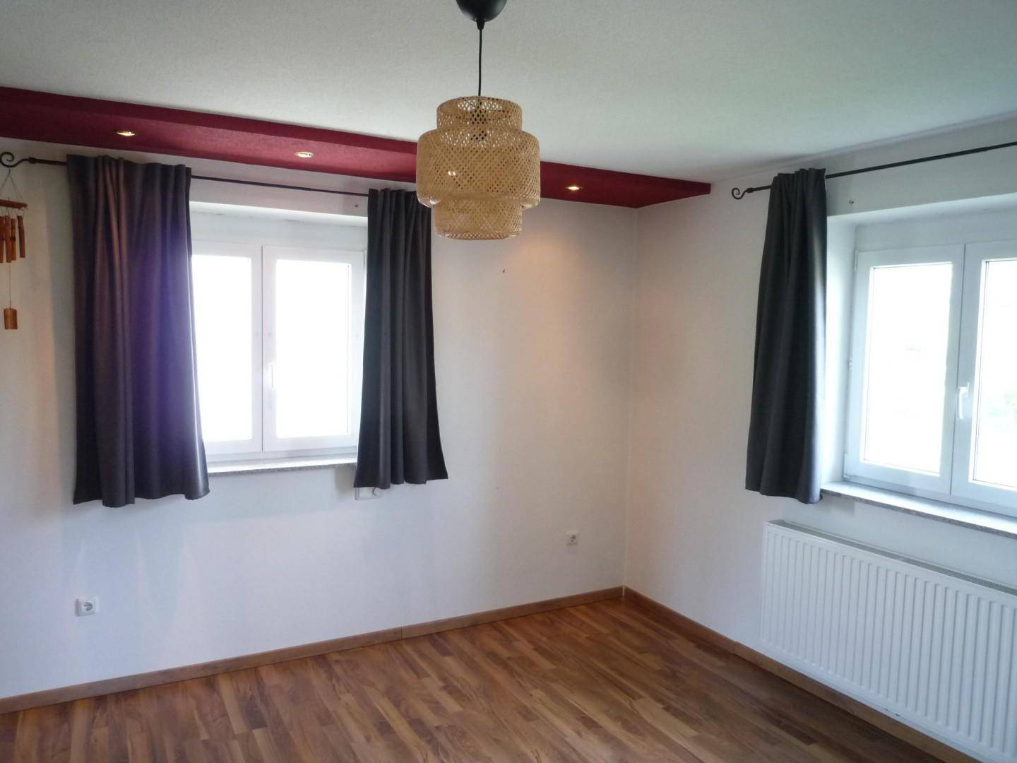 Helles Zimmer mit Laminatboden, weißen Wänden und einer Deckenbeleuchtung.