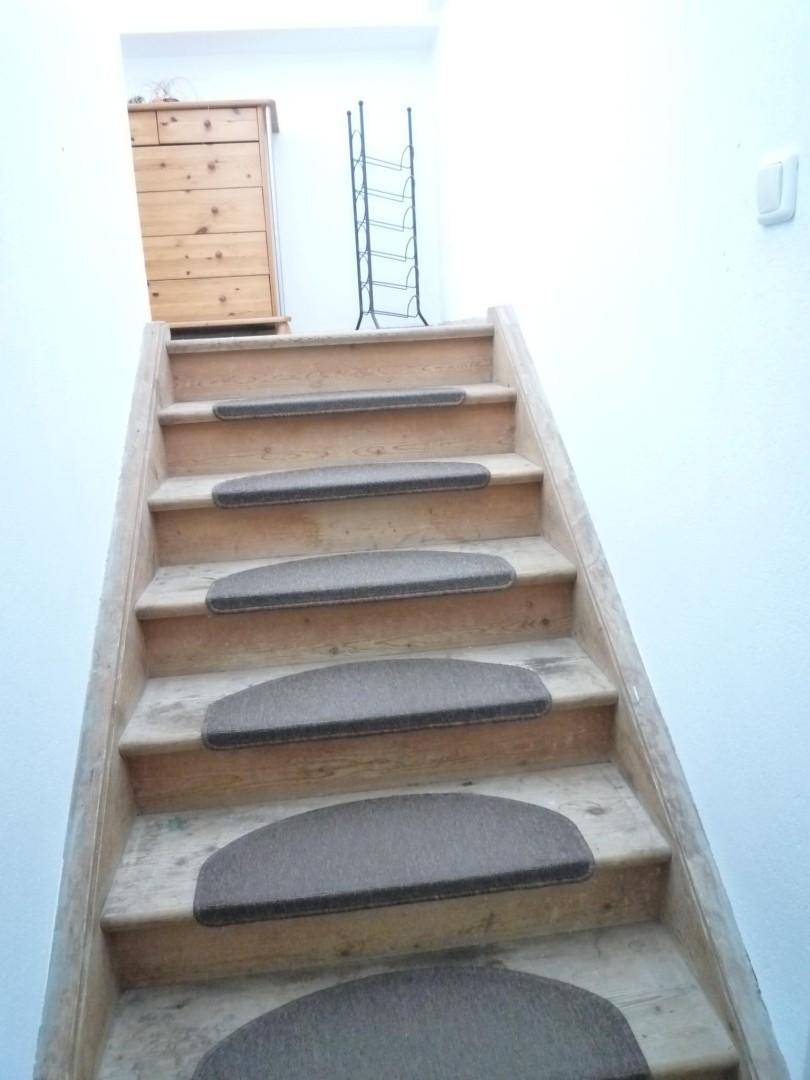 Holztreppe mit Teppichstufen, die in das obere Stockwerk führt.