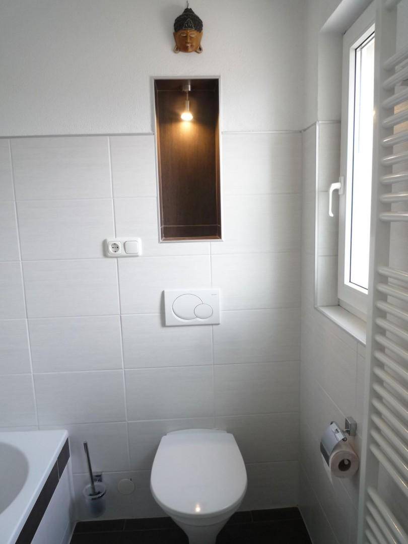 Badezimmer mit Toilette, Fenster und beheiztem Handtuchhalter.