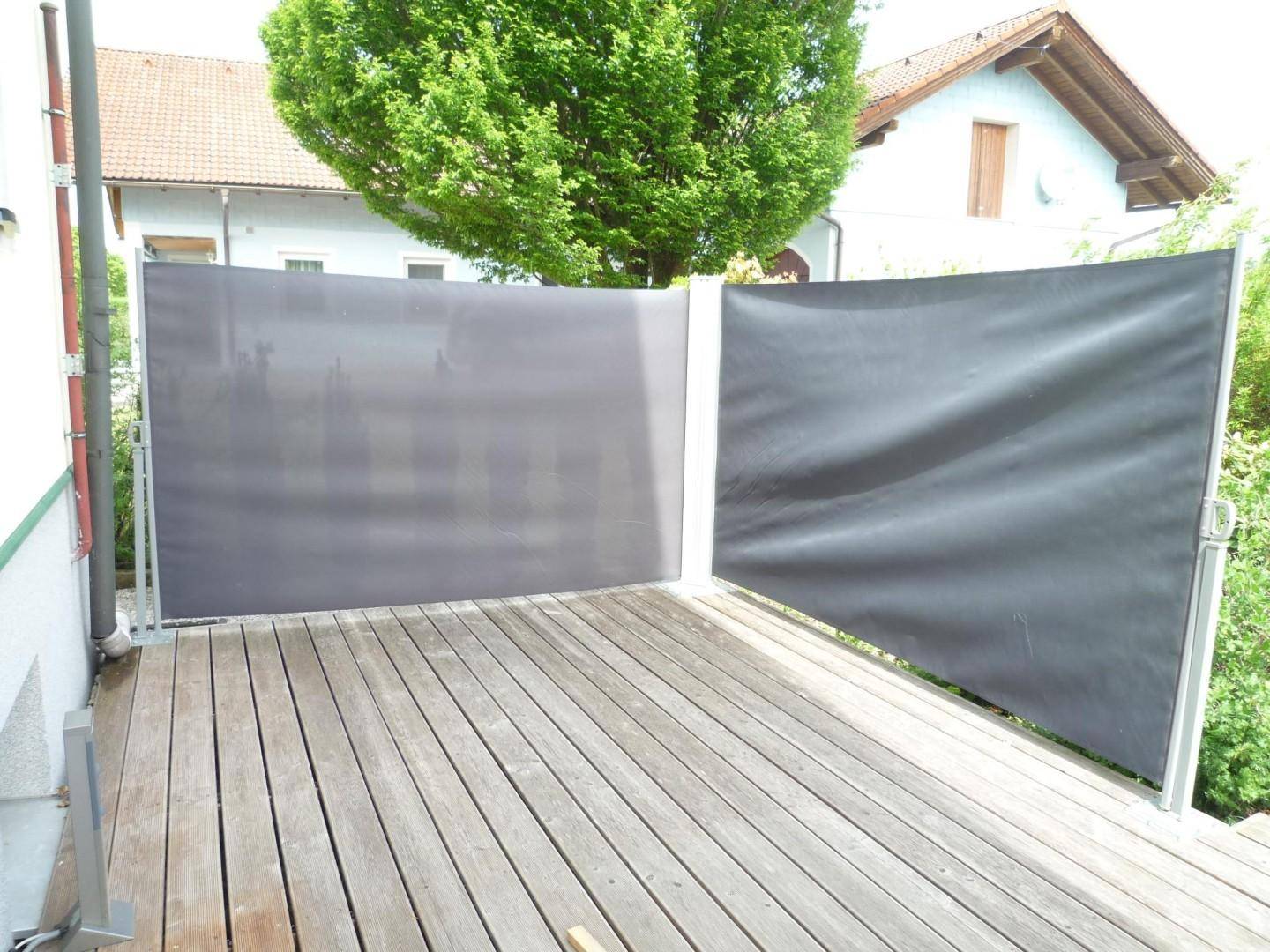 Holzterrasse mit seitlichen Sichtschutzwänden für mehr Privatsphäre im Freien.