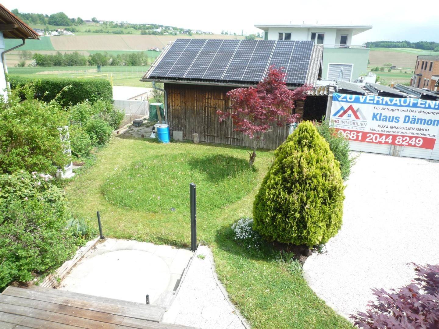 Gepflegter Gartenbereich mit Rasenfläche, Gartenhaus mit Solaranlage und weitem Blick ins Grüne.