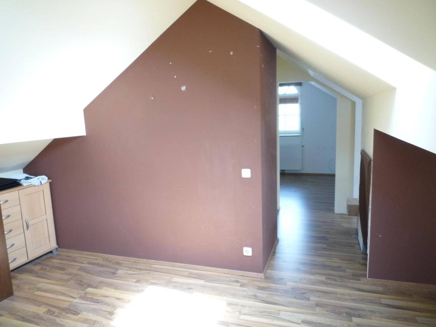 Dachgeschosszimmer mit schrägen Decken, Laminatboden und braun gestrichenen Wänden.