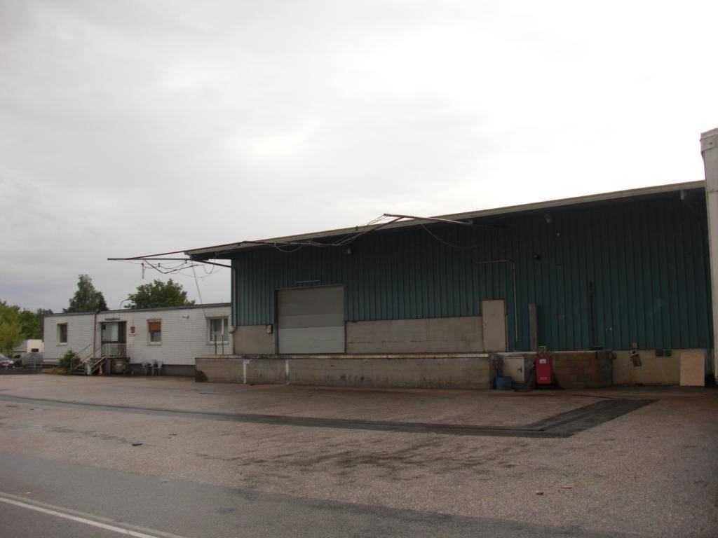 Laderampenbereich einer Lagerhalle mit angrenzenden modularen Bürocontainern und einem breiten Vorplatz.