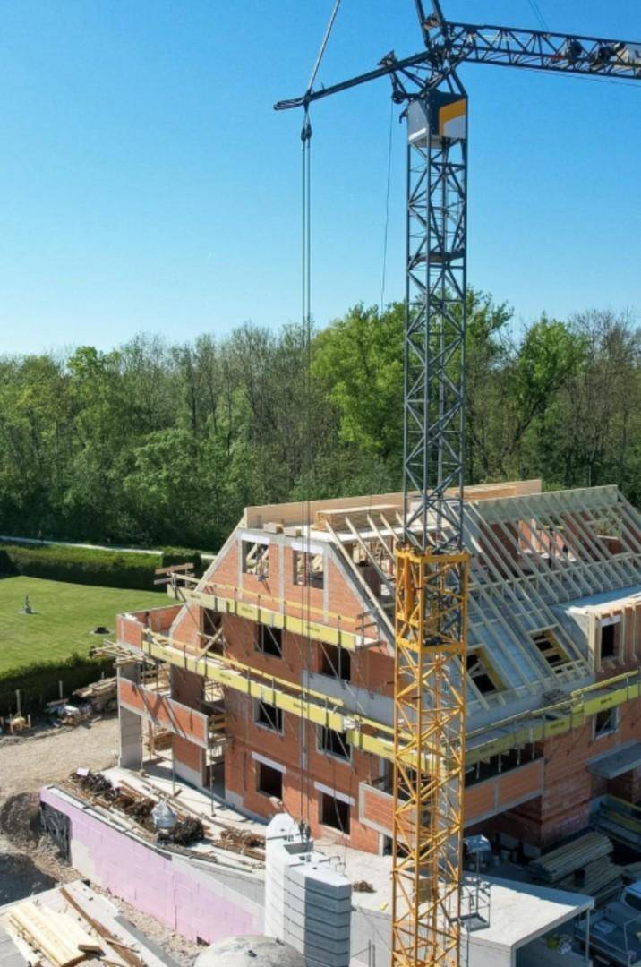 Baustelle eines Neubaus mit Kran und Rohbau in ländlicher Umgebung.
