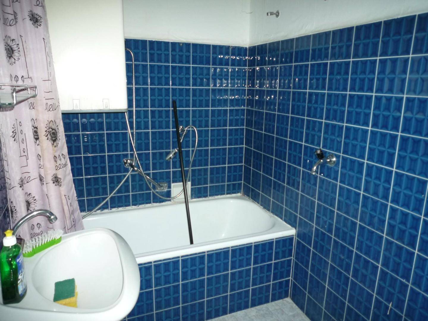 Badezimmer mit blauen Fliesen, einer Badewanne und einem Waschbecken im Vintage-Stil.