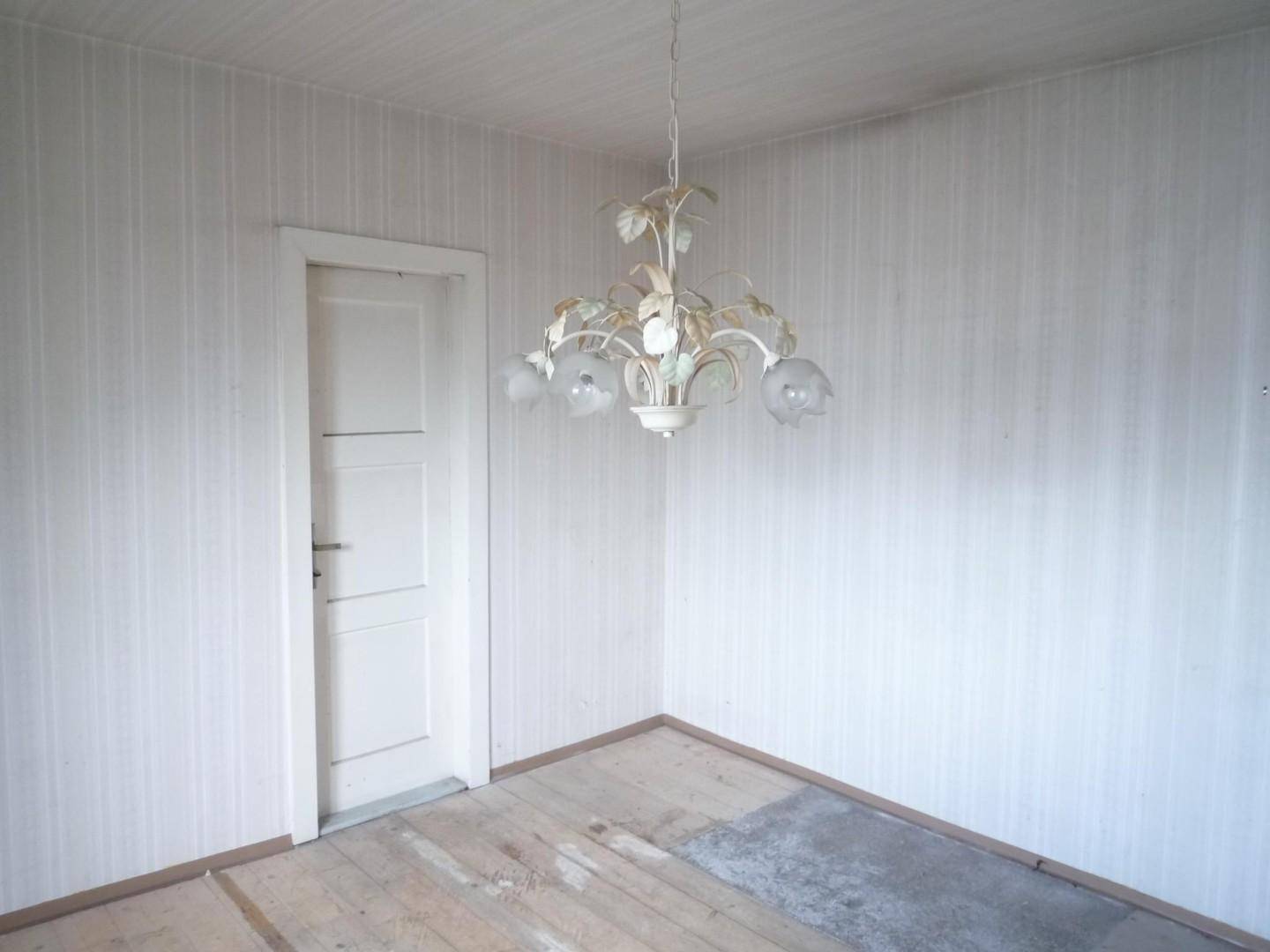 Heller Raum mit Holzdielenboden und weißer Tür, bereit für eine Neugestaltung.
