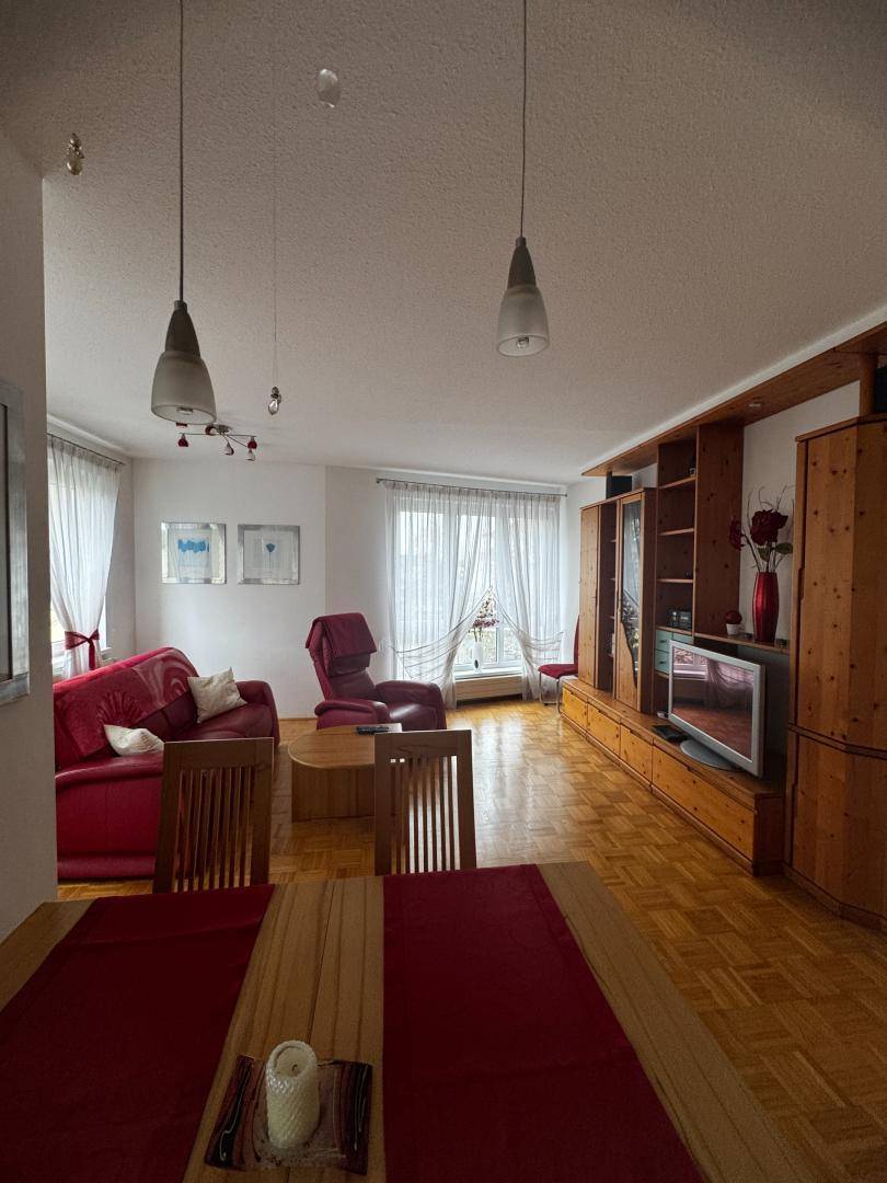 Geräumiger Wohn-Essbereich mit Parkettboden, Holzmöbeln und roten Akzenten im Dekor.