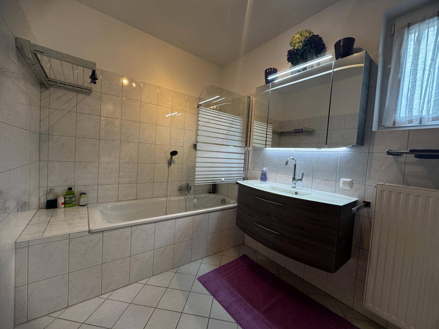 Modernes Badezimmer mit Badewanne, schwebendem Waschtisch und Spiegelschrank über dem Waschbecken.