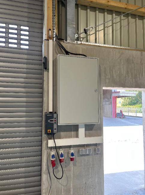 Detailansicht einer elektrischen Installation mit Schaltschrank und Steckdosen in einem Industriegebäude.