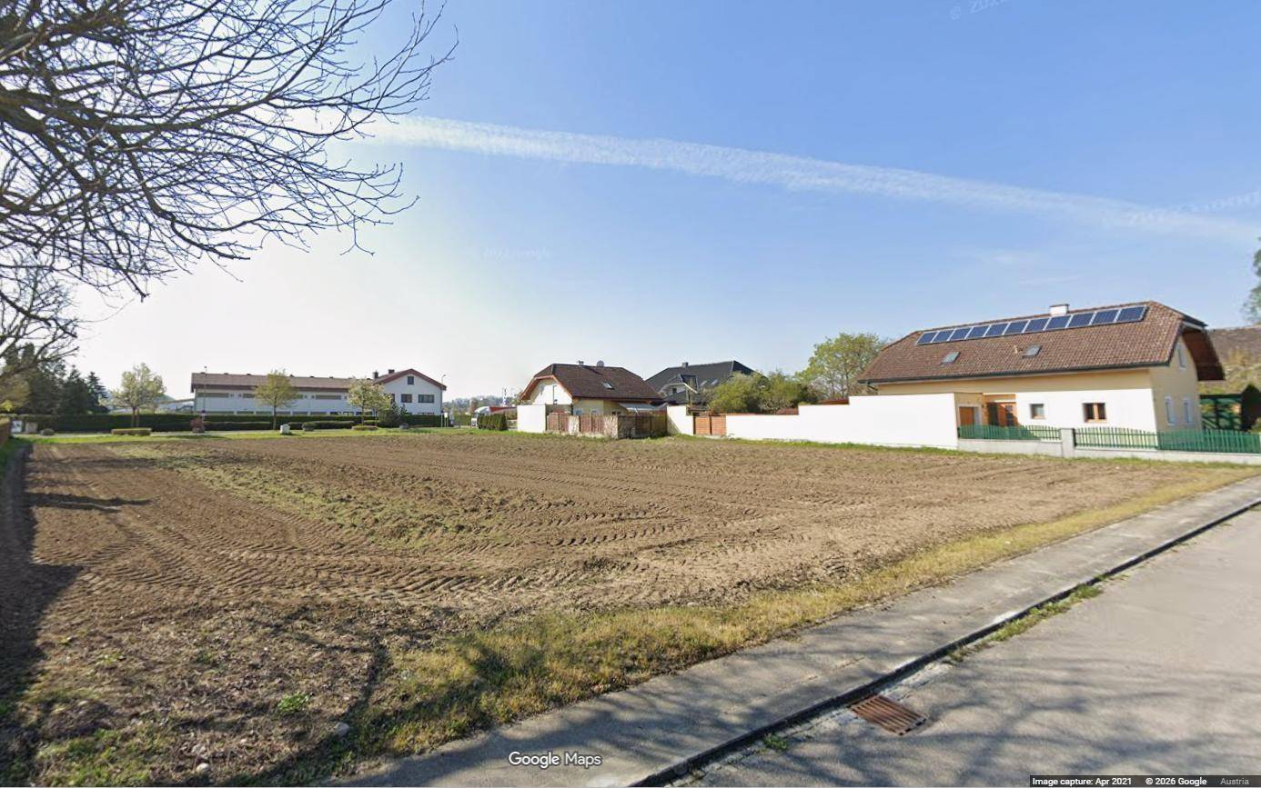 Geräumiges Grundstück mit brauner Erde, umgeben von Wohnhäusern in einer ländlichen Umgebung.