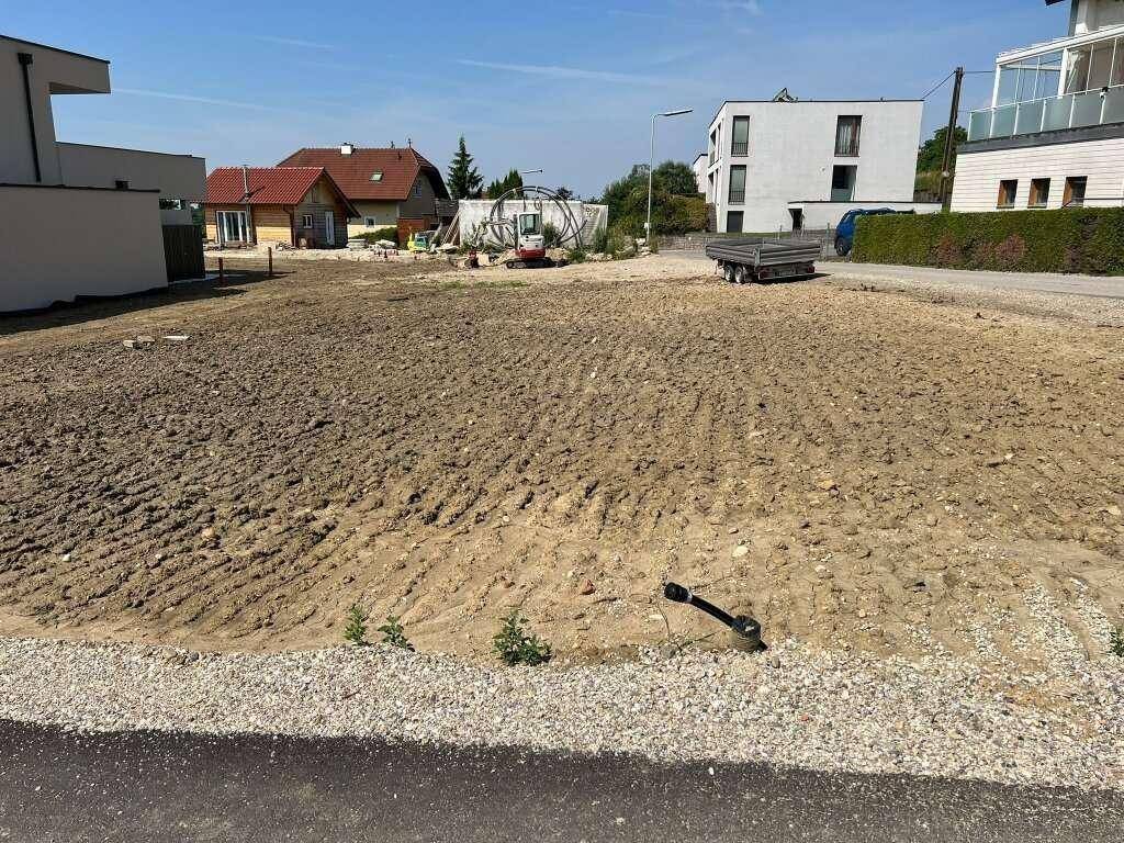 Unbebautes Grundstück mit verschiedenen Gebäuden im Hintergrund, darunter moderne und traditionelle Häuser.