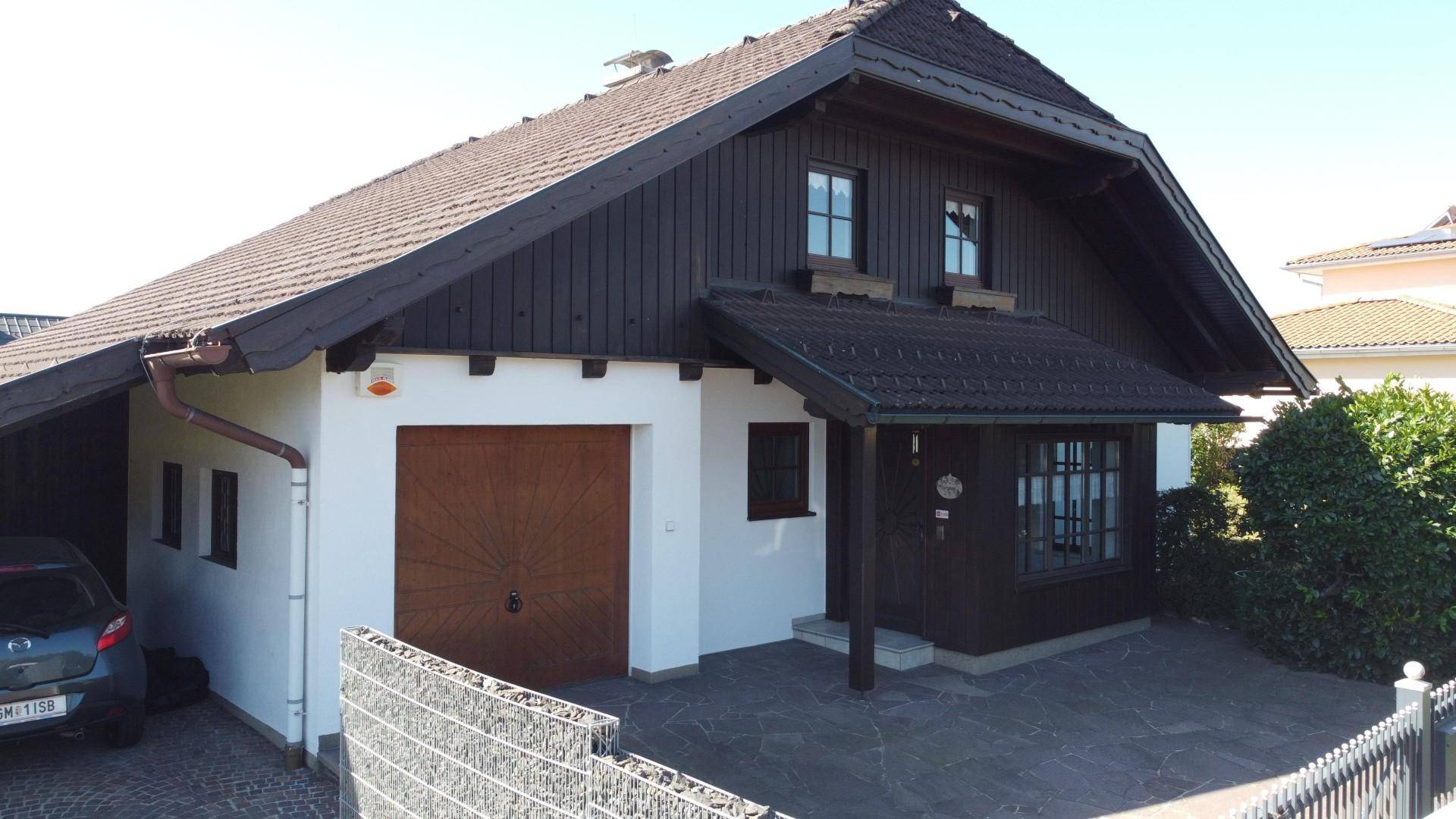 Vorderansicht des Hauses mit Garagentor, gepflasterter Einfahrt und einem kleinen Vorgartenbereich.